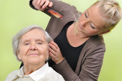 Homecare staff combing hair of elder woman
